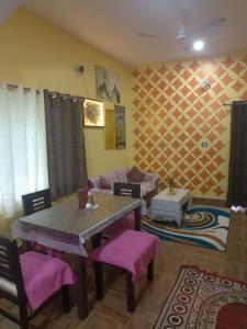 a living room with a table and purple chairs at Bhakti Suite in Deoghar