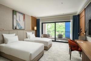 a hotel room with two beds and a desk at Mövenpick Hotel & Residences Teuta Kotor Bay in Kotor