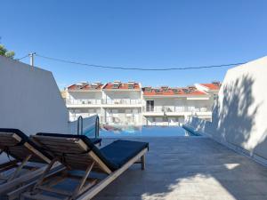 a balcony with two lounge chairs and a swimming pool at Villas Kaiafa “Ismini” in Polychrono