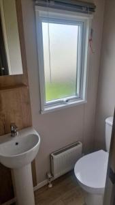 a bathroom with a sink and a toilet and a window at 3 Bed - Sleeps 8 - Family & Pet Friendly in Skegness