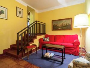 een woonkamer met een rode bank en een trap bij Belvilla by OYO Nobile in Tagliolo Monferrato