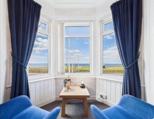 a room with two blue chairs and a table and windows at The Fossil Tree Hotel in Blackpool