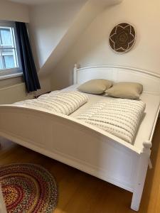 a white bed with two pillows and a clock on the wall at Strandvilla Zeegloed in Sint-Idesbald