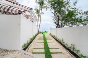 a white wall with a pathway with grass at Casa Lucia Resort Hotel in Oslob