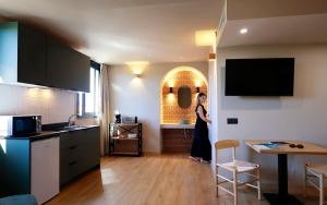 a woman standing in a kitchen with a table at Alcudia Boutique Apartments in Alcudia