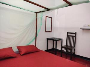a bedroom with a bed and a table and a chair at Eastwind Surf Camp - Surf & Stay in Arugam Bay +115 photos