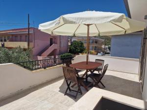 un tavolo e sedie con un ombrellone su un balcone di Paule mare a La Caletta