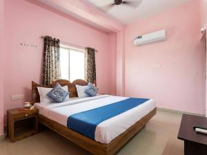 a bedroom with a bed with pink walls and a window at Tapasya Palace in Gorakhpur