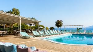 a swimming pool with lounge chairs and the ocean at Agnes Beach Hotel Apartments in Kavos