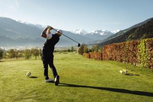 a man swinging a golf club on a golf course at Appartement Carmen in Uderns