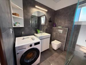 a bathroom with a washing machine and a sink at Kalithea Apartement in Palekastron +16 photos