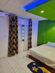 a bedroom with a bed and a green wall at Le Rêve d'Or in Lomé