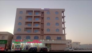 a large building with cars parked in front of it at Sahalnoot flats in Salalah