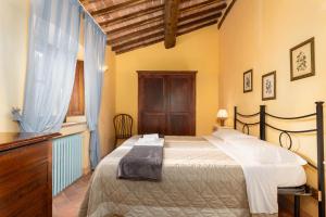 a bedroom with a bed with a dresser and a window at Borgo Tignano in Casole dʼElsa