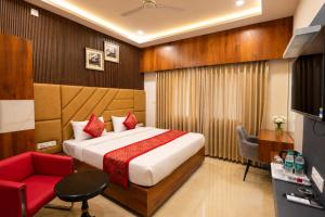 a hotel room with a bed and a red chair at hotel pride & restaurant in Dabok +38 photos