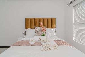 a white bed with white sheets and flowers on it at Royalty Suites in Chartwell Sandton in Chartwell +53 photos