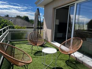three chairs and an umbrella on a balcony at Horizon Lac - wifi - parking in Morges