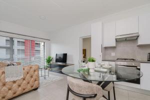 a kitchen and living room with a glass table and chairs at Royalty Suites in Chartwell Sandton in Chartwell