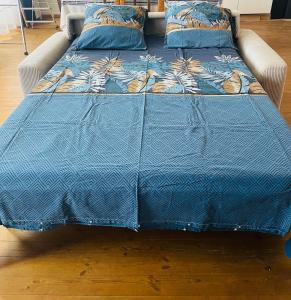a bed with a blue comforter and a couch at Jungle Gite in Fumel