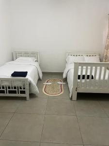 a bedroom with two beds and a rug on the floor at Suzie's Nest 2 in Lilongwe