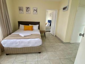 a bedroom with a large bed with an orange pillow at Oceanic Apartment - Ocean views - Self-Catering in Durban +31 photos