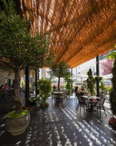 a patio with tables and chairs under a straw roof at Hotel Rubis in Ferizaj