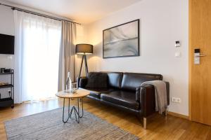 a living room with a black leather couch and a table at WeinHotel Fritz Walter in Niederhorbach