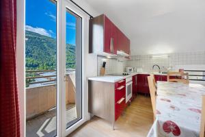 a kitchen with red cabinets and a large window at Appartement Aime La Plagne in Aime-La Plagne