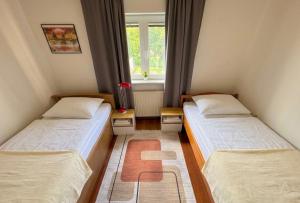 two beds in a small room with a window at Hava apartment in Sarajevo