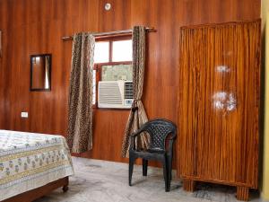 a bedroom with a chair and a window at Ranibagh Riverview Retreat in Kāthgodām