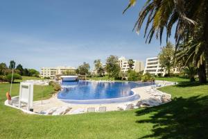 a swimming pool in a park with buildings in the background at Marachique Villa - Torralvor in Alvor