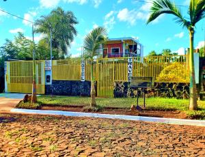 a yellow fence with a house behind it at Hotel Travel Encarnación in Encarnación