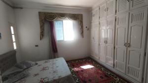 a bedroom with a bed and a window and a door at Maison Lyne in Hammamet