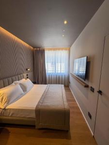 a bedroom with a large bed and a flat screen tv at The Q House in Foligno