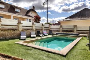 a swimming pool with two chairs and a fence at Gîte Le Rabelais in Thésée