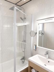a white bathroom with a shower and a sink at Logis Hôtel Restaurant Europa in Maussac