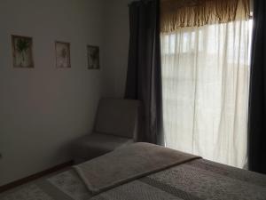 a bedroom with a bed and a window with a chair at Garça-Real 2 in Vale de Madeiros