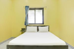 a bed in a room with a window at Hotel O Raj Guest House in Akola
