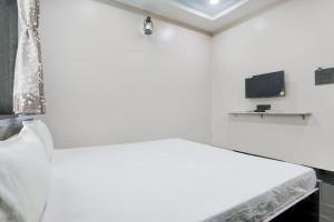 a white room with a bed and a tv at Hotel O Raj Guest House in Akola