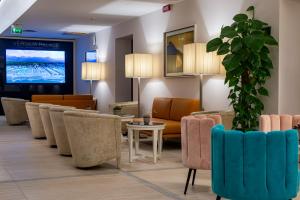 a lobby with a waiting room with chairs and a tv at Versilia Palace Hotel in Marina di Pietrasanta