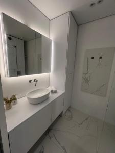 a white bathroom with a sink and a mirror at Manhattan Comfort in Ivano-Frankivsk