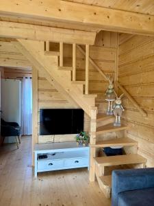 a living room with a staircase with a television in a wooden wall at Chata u Drwala Święta Lipka in Święta Lipka