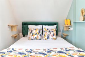 a bedroom with a bed with a green headboard and pillows at Gîte du Merlin in Plumergat