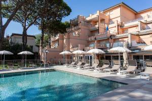 a hotel with a swimming pool with chairs and umbrellas at Versilia Palace Hotel in Marina di Pietrasanta
