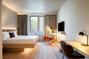 a hotel room with a bed and a desk with a computer at Moxy Budapest Downtown in Budapest +86 photos