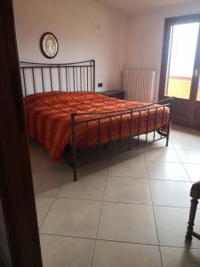 a bedroom with a bed with an orange blanket and a clock at Domo Mea in Orgosolo