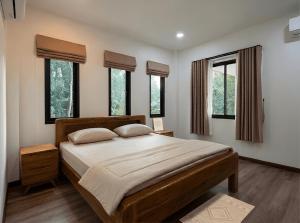 a bedroom with a large wooden bed with windows at Soul House - Stay Beautifully in Ko Kong Nui