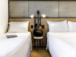 two beds with a guitar on the wall between them at ibis Ribeirao Preto Vila do Golf Shopping in Ribeirão Preto