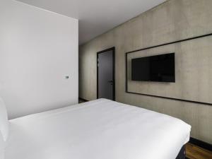 a bedroom with a white bed and a flat screen tv at ibis Bridgwater, M5 Jct23 in Bridgwater