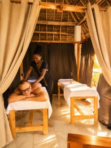 a woman giving a man a massage in a bed at Smile Boutique Beach hotel in Nungwi